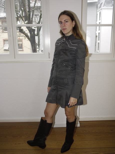 Vintage Diesel zip-up mini dress in faded black denim, utility-style jacket dress with contrast stitching and stand-up collar, Y2K grunge aesthetic, styled with black boots indoors.