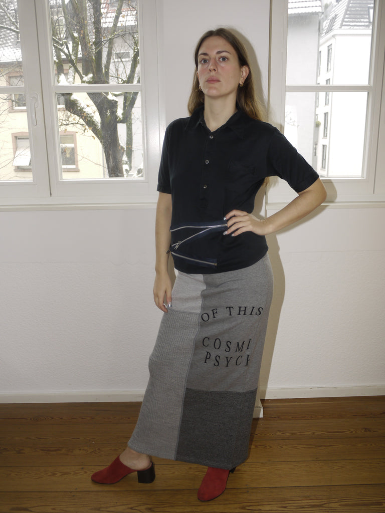 Vintage Miu Miu black short-sleeve knit top with a classic collar and button-down front, featuring a slightly cropped fit. Styled with a grey maxi skirt featuring statement text print for a playful yet refined look.