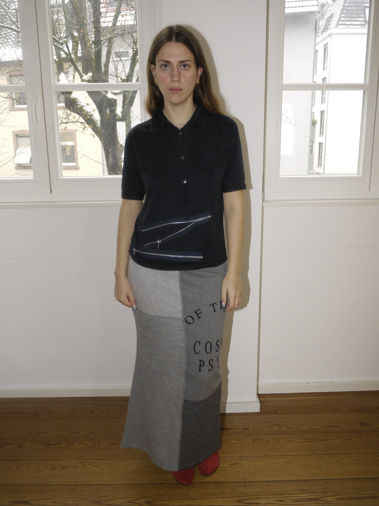 Vintage Miu Miu black short-sleeve knit top with a classic collar and button-down front, featuring a slightly cropped fit. Styled with a grey maxi skirt featuring statement text print for a playful yet refined look.