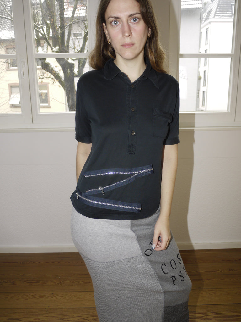 Vintage Miu Miu black short-sleeve knit top with a classic collar and button-down front, featuring a slightly cropped fit. Styled with a grey maxi skirt featuring statement text print for a playful yet refined look.