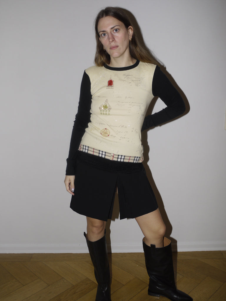 Vintage black midi skirt with low-rise fit and textured waistband detail. Styled with a knit vest and boots for a playful, eclectic look with slight Y2K and craftcore vibes.