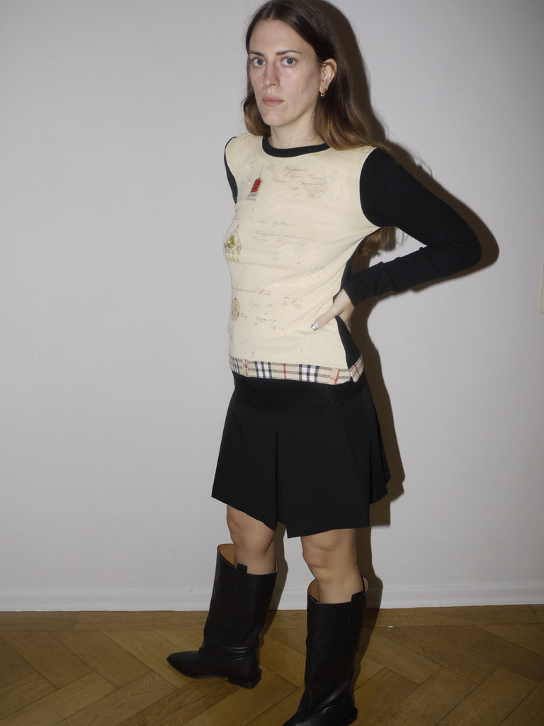 Vintage black midi skirt with low-rise fit and textured waistband detail. Styled with a knit vest and boots for a playful, eclectic look with slight Y2K and craftcore vibes.