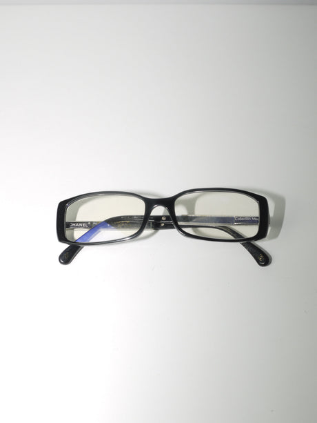 Vintage Chanel blue light filter glasses with rectangular black acetate frame, subtle logo detail, elegant and functional designer eyewear for screen protection, shown flat and worn by model.