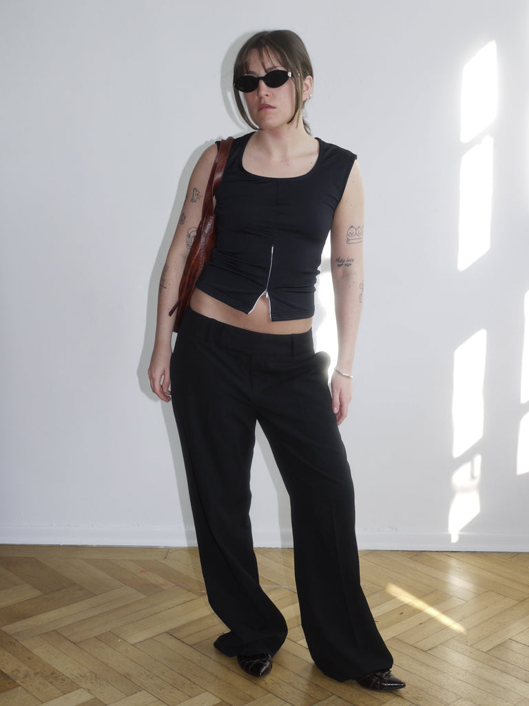 Black leather bag with hardware details worn crossbody – paired with mesh and crop top for a bold Y2K vibe