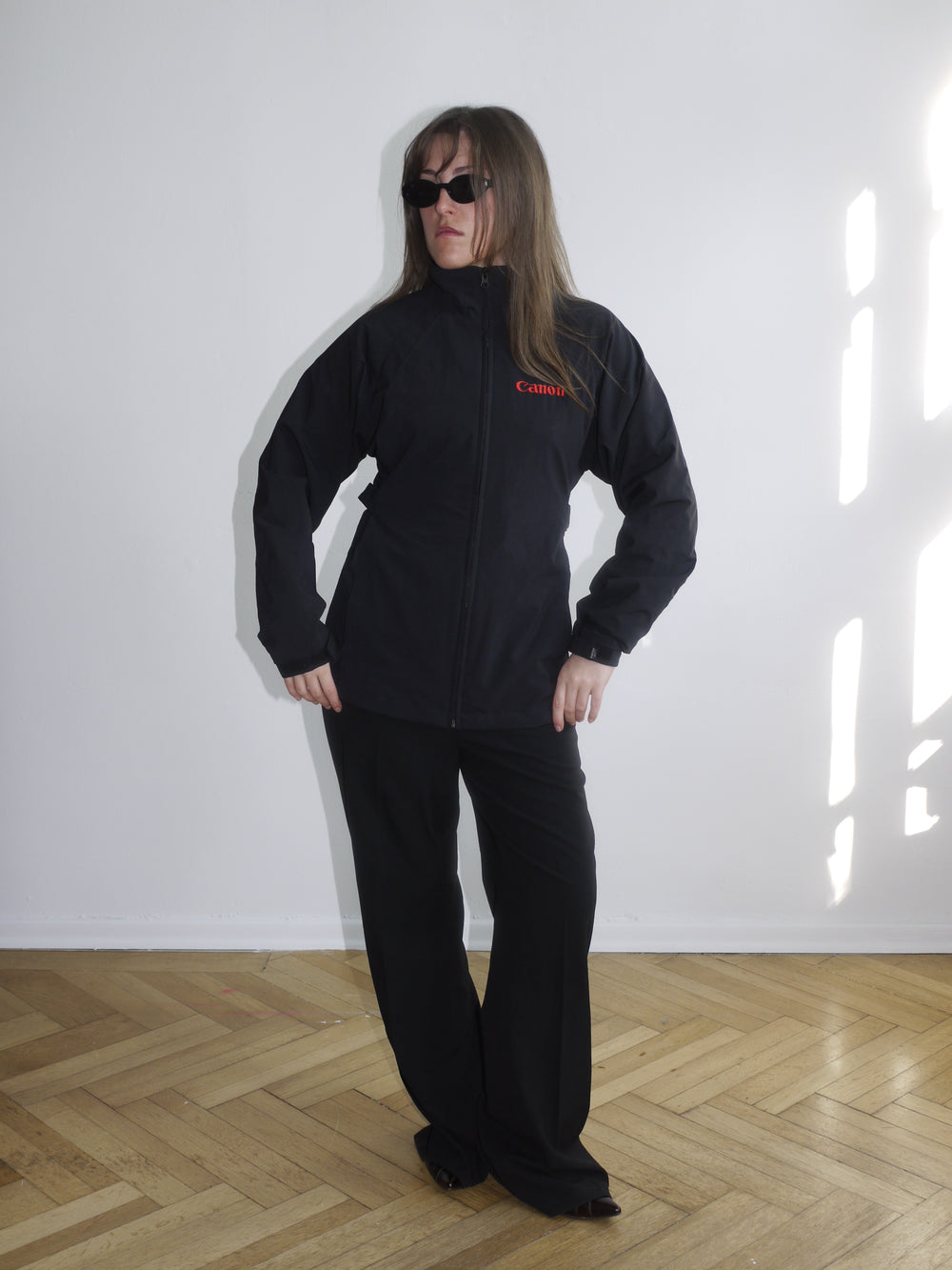Black Canon branded zip-up jacket with red logo embroidery on the chest, worn with matching black pants. Sporty and utilitarian look with a boxy fit.