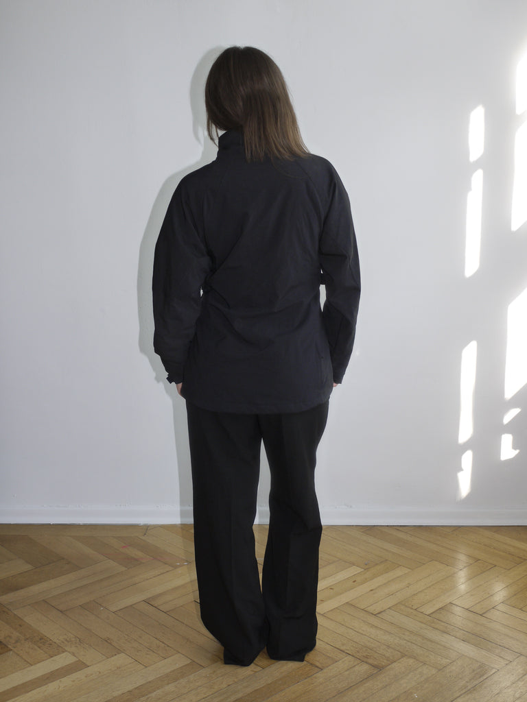 Black Canon branded zip-up jacket with red logo embroidery on the chest, worn with matching black pants. Sporty and utilitarian look with a boxy fit.