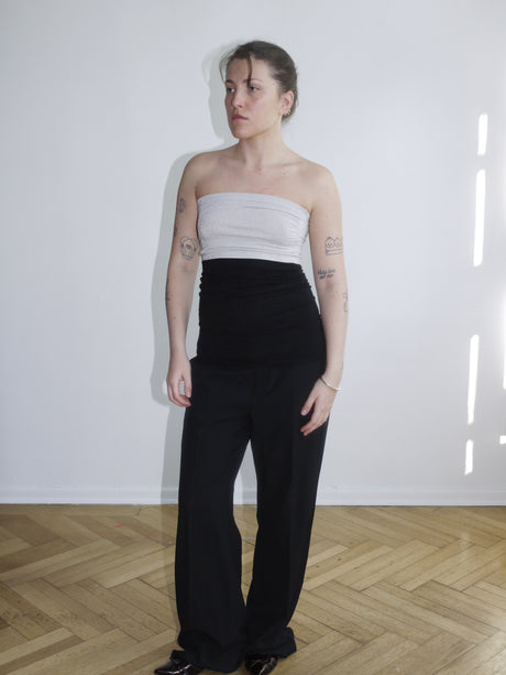 Strapless white mesh top with sheer overlay and structured bust – styled with low-rise black trousers for a sleek contrast.