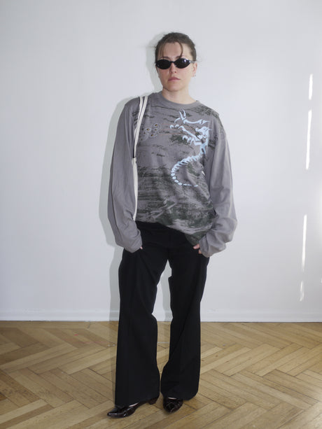 Oversized grey long sleeve with white dragon print on the front – styled with wide-leg black pants for a bold streetwear look.