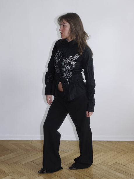 Black Desigual shirt with embroidered floral details and patch textures – styled with black trousers for a bold look.