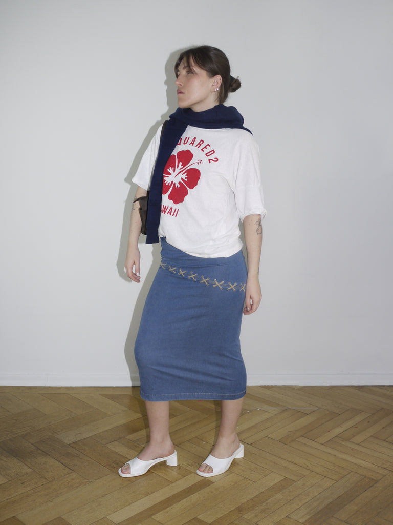 White Dsquared² t-shirt with bold red maple leaf and “Hawaii” print on the front. Paired with a vintage low-rise denim midi skirt and a navy sweater casually draped over the shoulders.