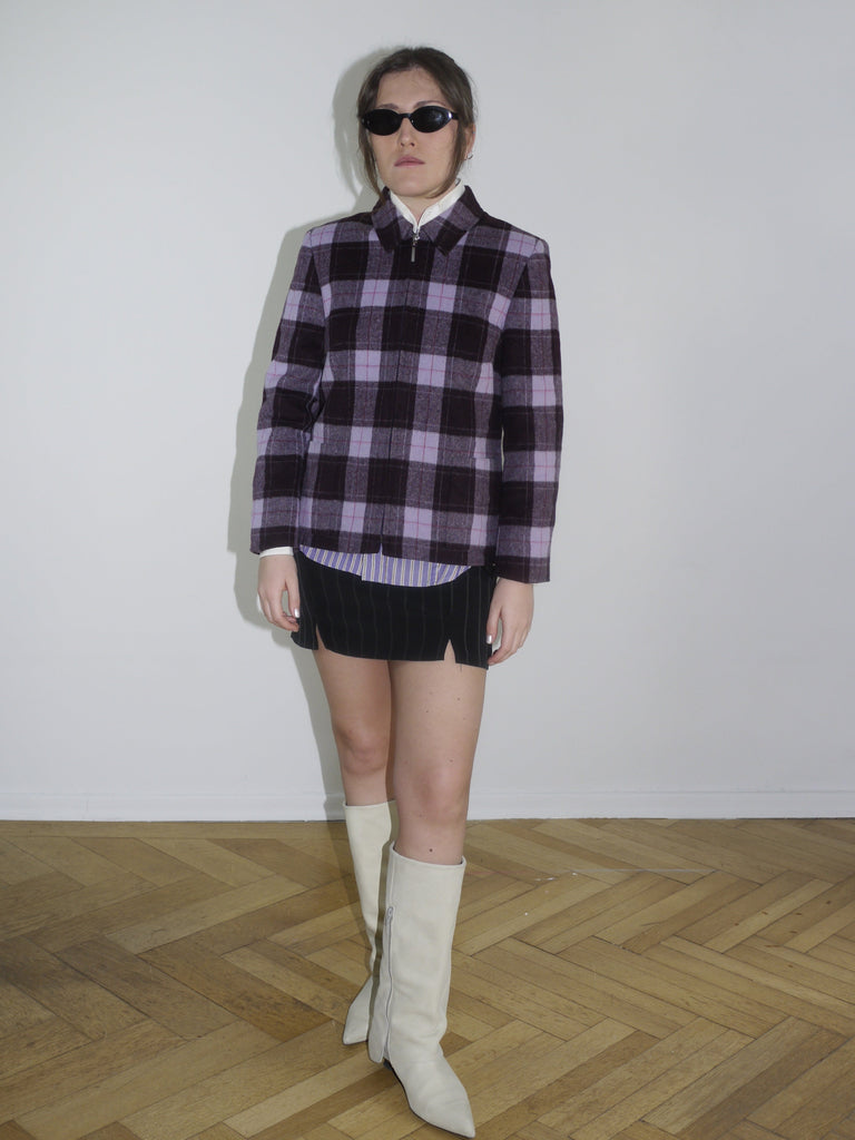 Vintage checked jacket in purple and black tones with structured shoulders, styled over a white-collared shirt and pinstriped mini skirt. Dsquared-inspired layering look for early spring.