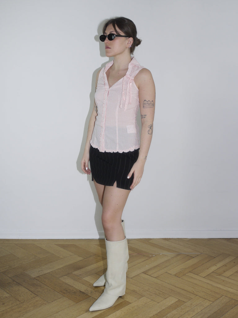 Light pink ruched sleeveless blouse with pointed collar and deep V-neck, styled with a pinstriped mini skirt. Early 2000s-inspired look with Gimaguas vibes.