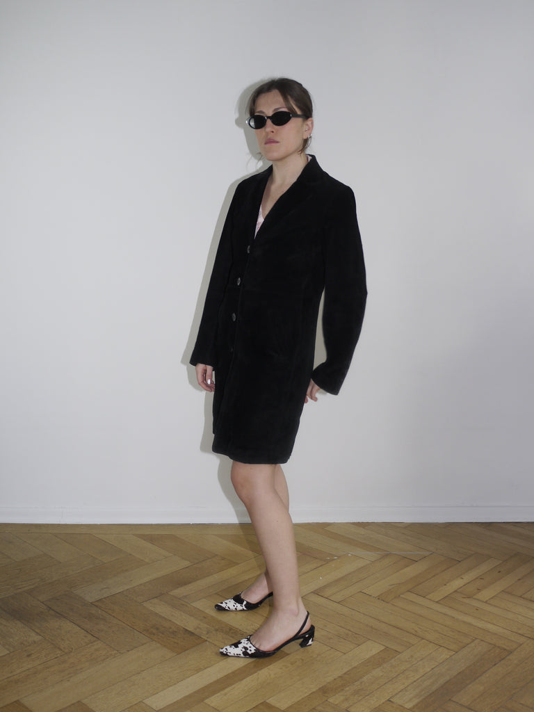 Black vintage leather coat with minimalist cut, styled with cow-print kitten heels. A sleek Margiela-inspired silhouette, perfect for spring layering.