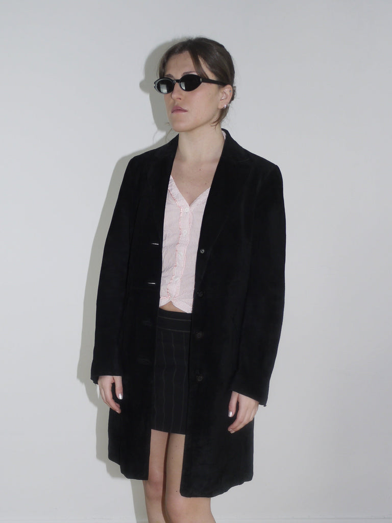 Black vintage leather coat with minimalist cut, styled with cow-print kitten heels. A sleek Margiela-inspired silhouette, perfect for spring layering.