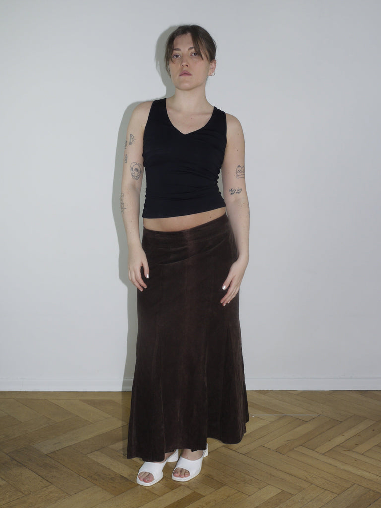 Black sleeveless backless top with long hanging fabric bands, styled with a brown flared suede maxi skirt. A Cop Copine-inspired silhouette, perfect for spring layering