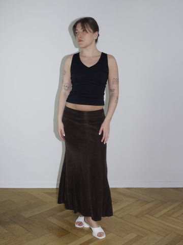 Black sleeveless backless top with long hanging fabric bands, styled with a brown flared suede maxi skirt. A Cop Copine-inspired silhouette, perfect for spring layering