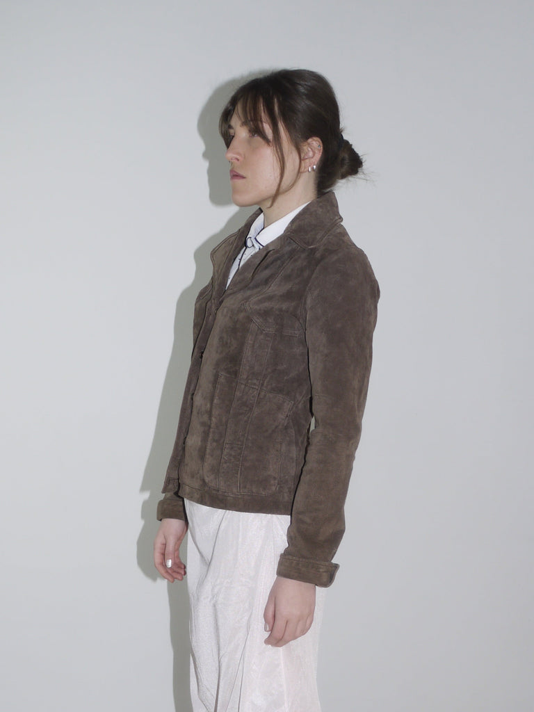 Model wearing a cropped brown faux fur jacket over a soft white vintage-style dress and black leather boots – Miu Miu inspired layered look with retro femininity.