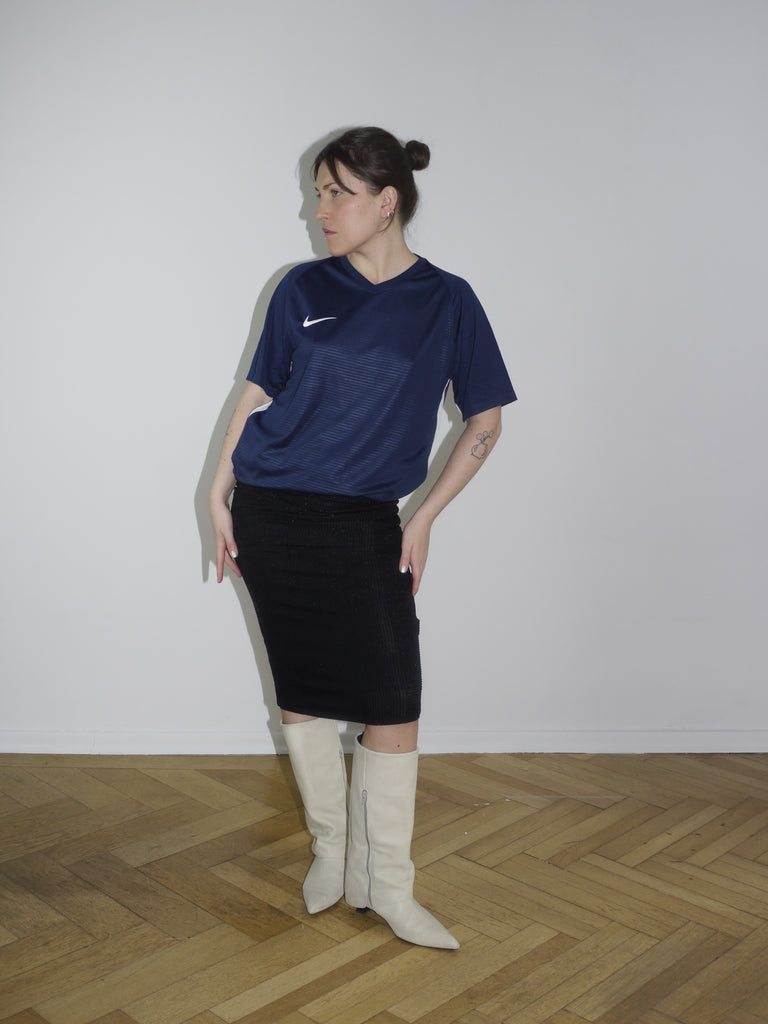 Navy blue Nike football jersey paired with a fitted black midi skirt and off-white vintage boots. Styled in a sporty-meets-minimal way, reminiscent of early 2000s streetwear and Y2K revival