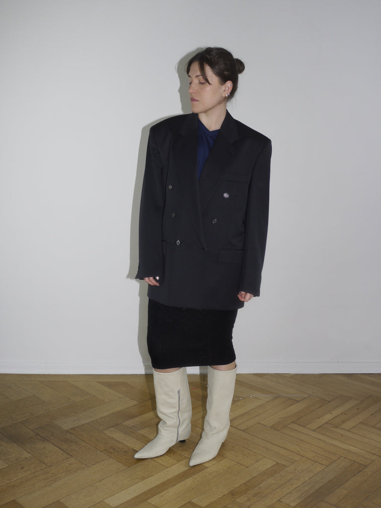 Vintage black oversized blazer with double-breasted buttons and sharp shoulders, styled with a midi pencil skirt and off-white boots. Inspired by Maison Margiela and Dries Van Noten tailoring.