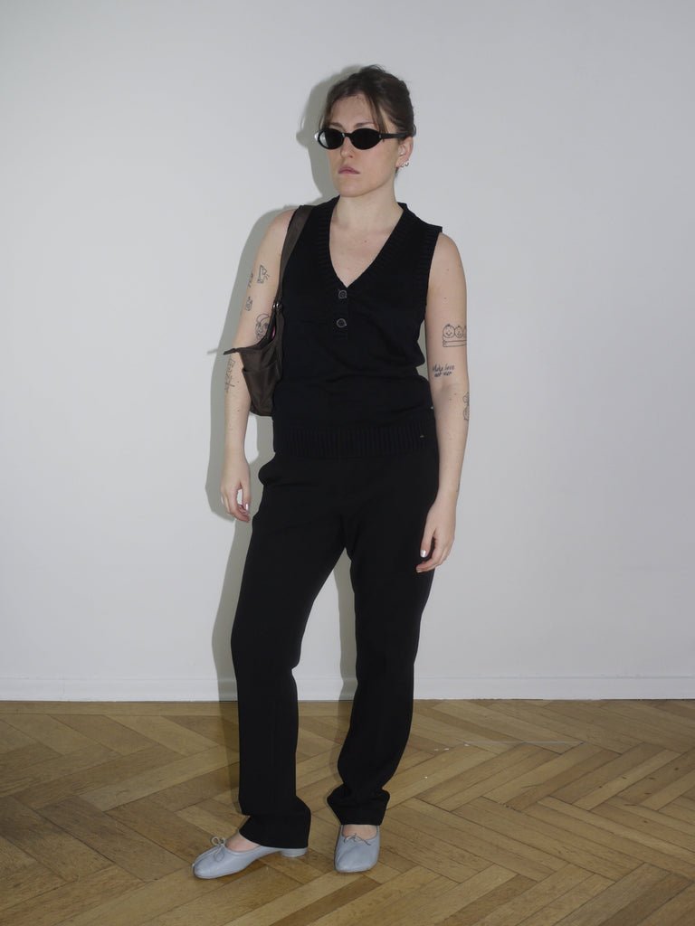 Front view of fitted sleeveless black top styled with straight-leg pants and white boots – clean silhouette with Diesel edge