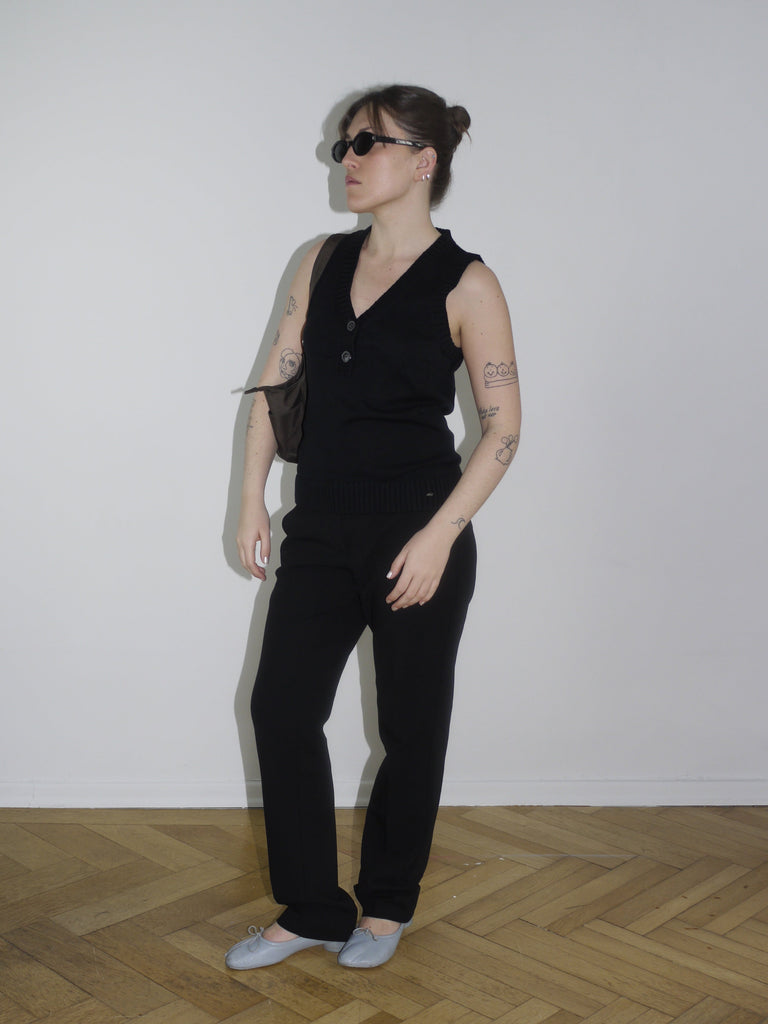 Model wearing a black sleeveless asymmetric top with deep V-neck and structured fit – Margiela-inspired minimalism with a twist