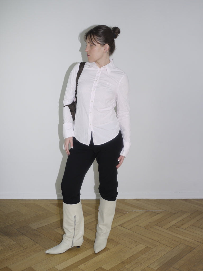 Model wearing vintage-style pink ruched shirt tucked into black pants with boots – inspired by Dsquared2 early collections.