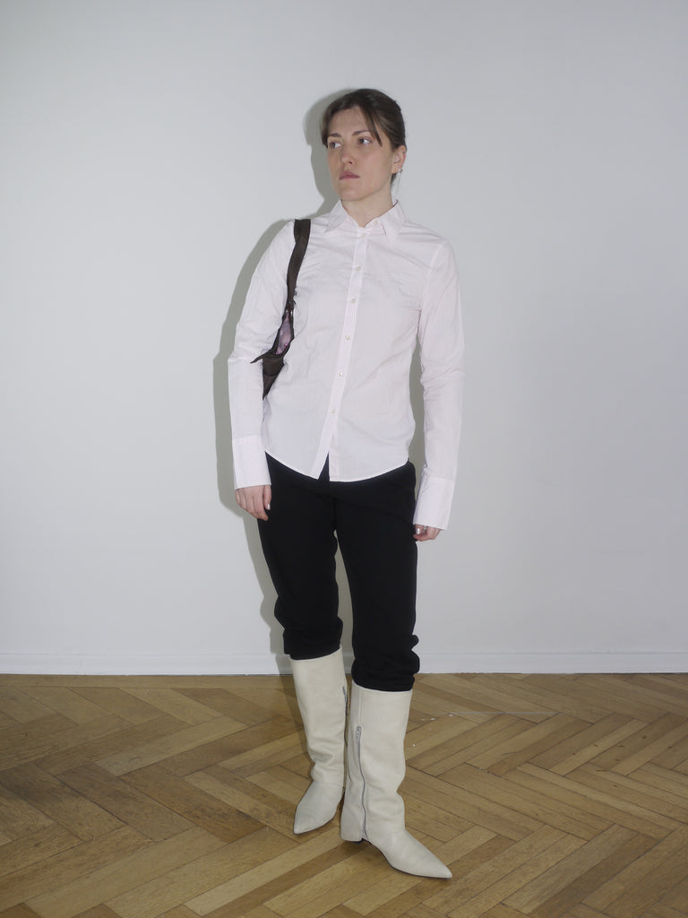 Relaxed outfit with black trousers, pink fitted shirt and structured bag – refined streetwear meets 2000s Diesel aesthetic.