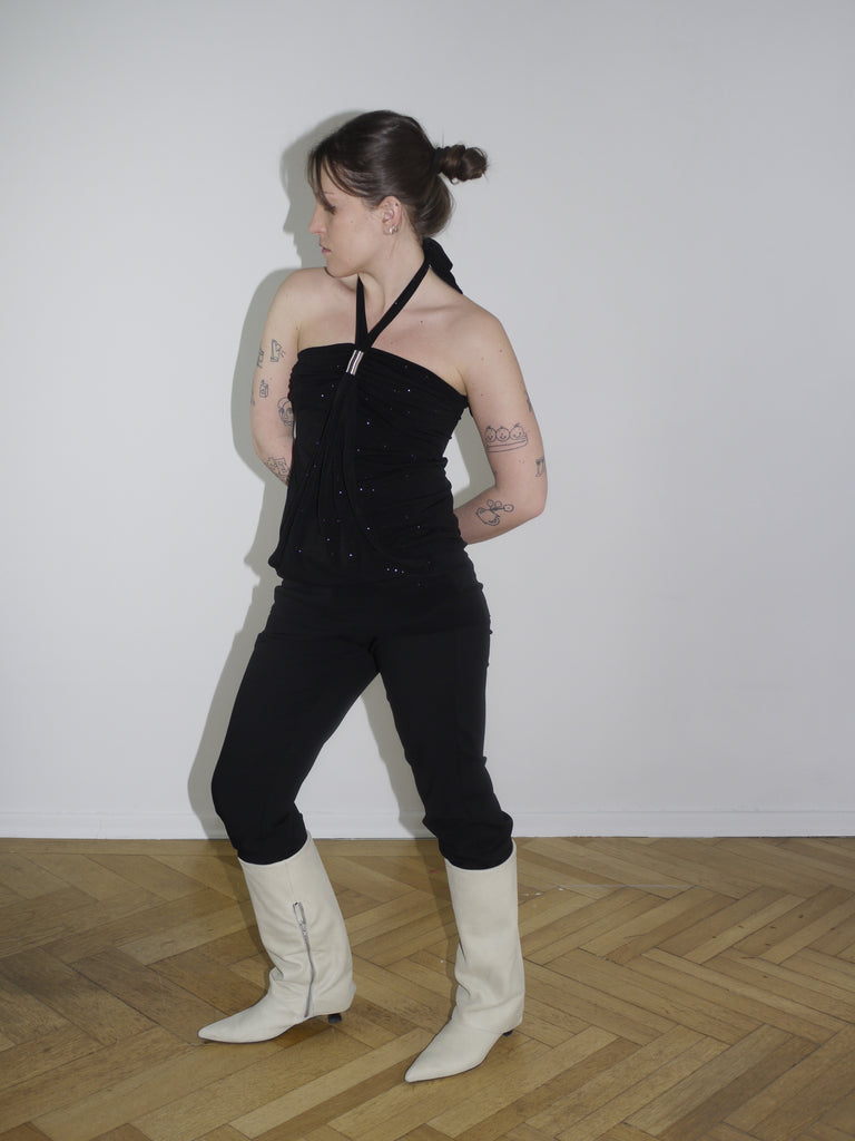 Back view of black top with open back and glossy texture – styled with knee-high boots.