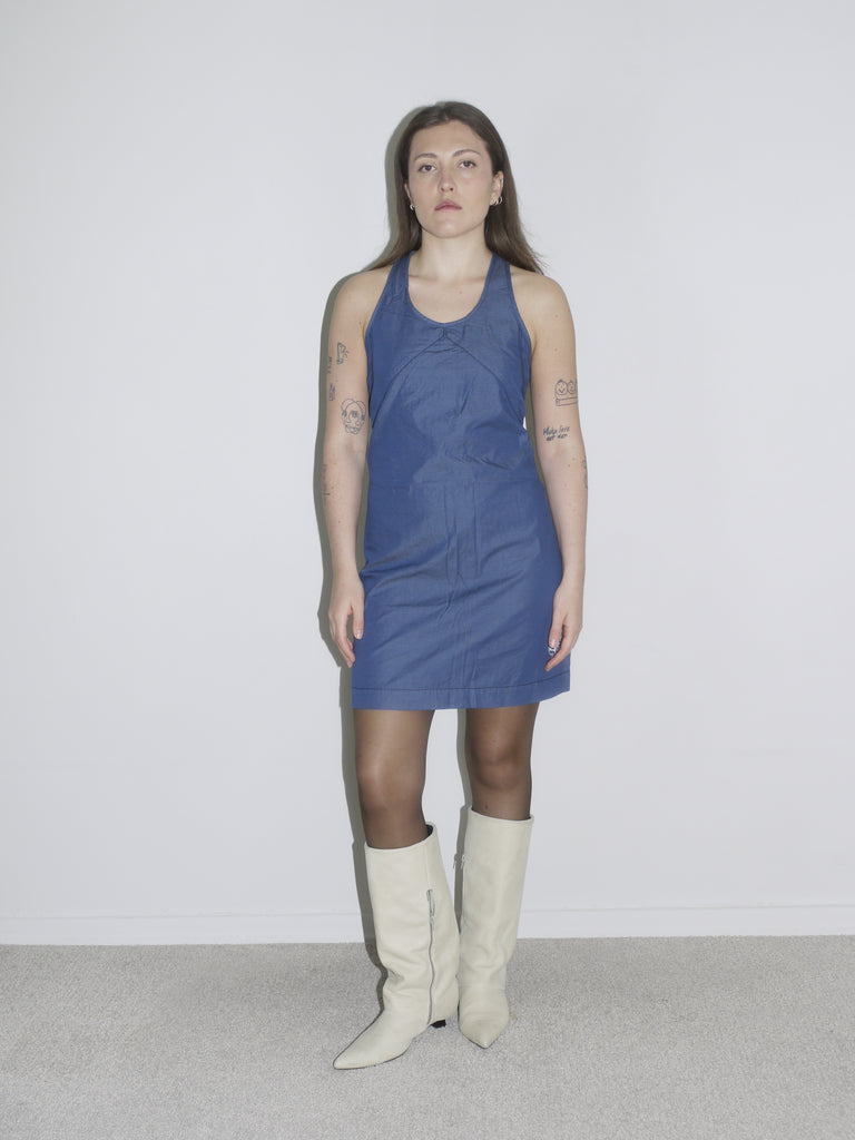 Model in a fitted dark blue halterneck mini dress by G-Star, styled with off-white knee-high boots – a sleek Y2K-inspired silhouette with utilitarian edge.