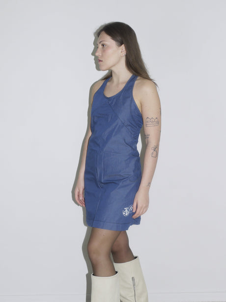 Model in a fitted dark blue halterneck mini dress by G-Star, styled with off-white knee-high boots – a sleek Y2K-inspired silhouette with utilitarian edge.