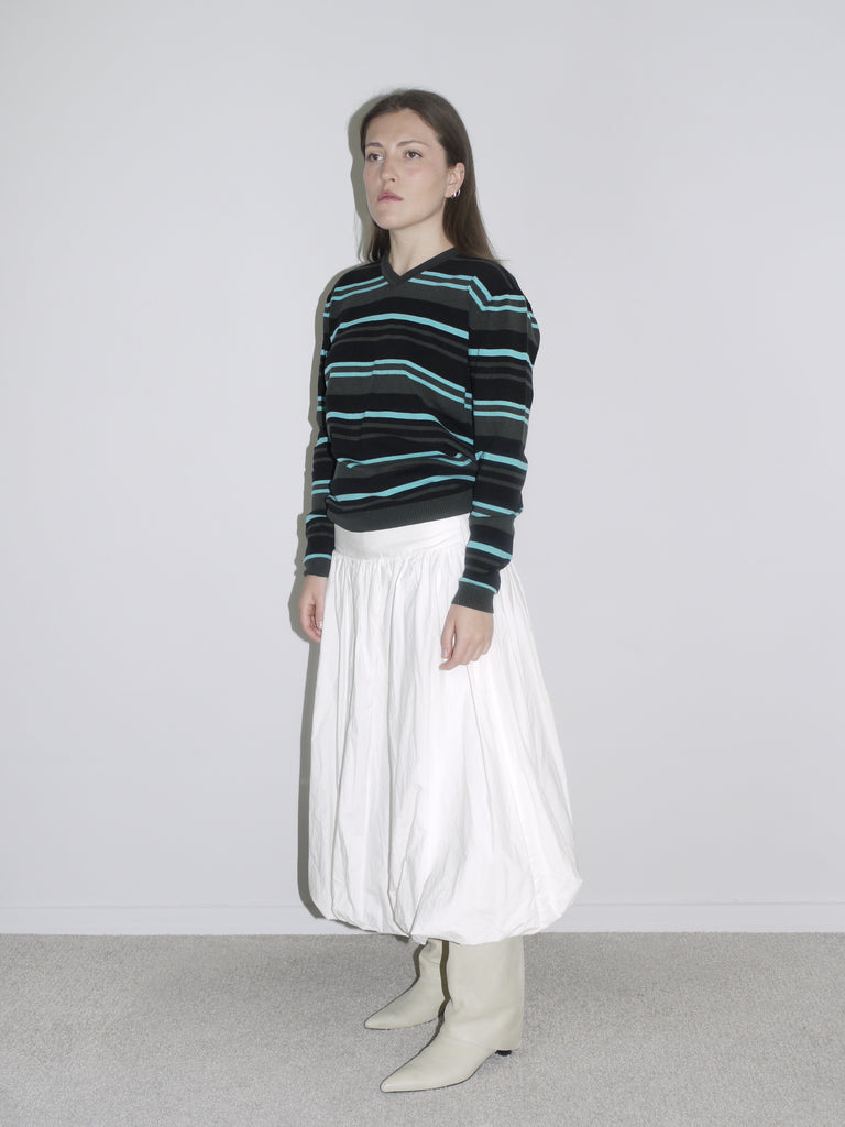 Model wearing a black long sleeve with mint and blue horizontal stripes, tucked into a voluminous white balloon skirt and styled with off-white cowboy boots. A laid-back vintage look blending skater Y2K with Cocaletto’s signature softness.