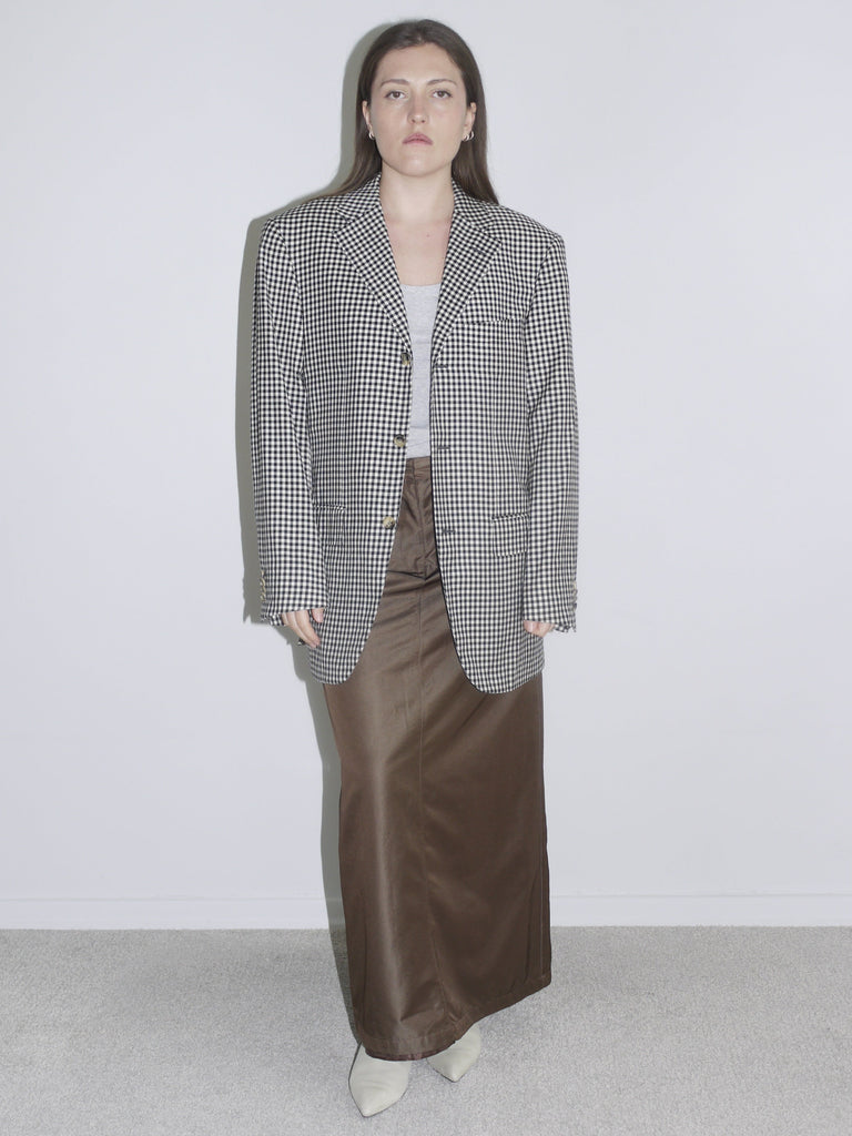 Model wearing an oversized checkered blazer paired with wide brown trousers – bold look with bright orange lipstick and pink faux fur detail, inspired by Maison Margiela and 90s editorials.