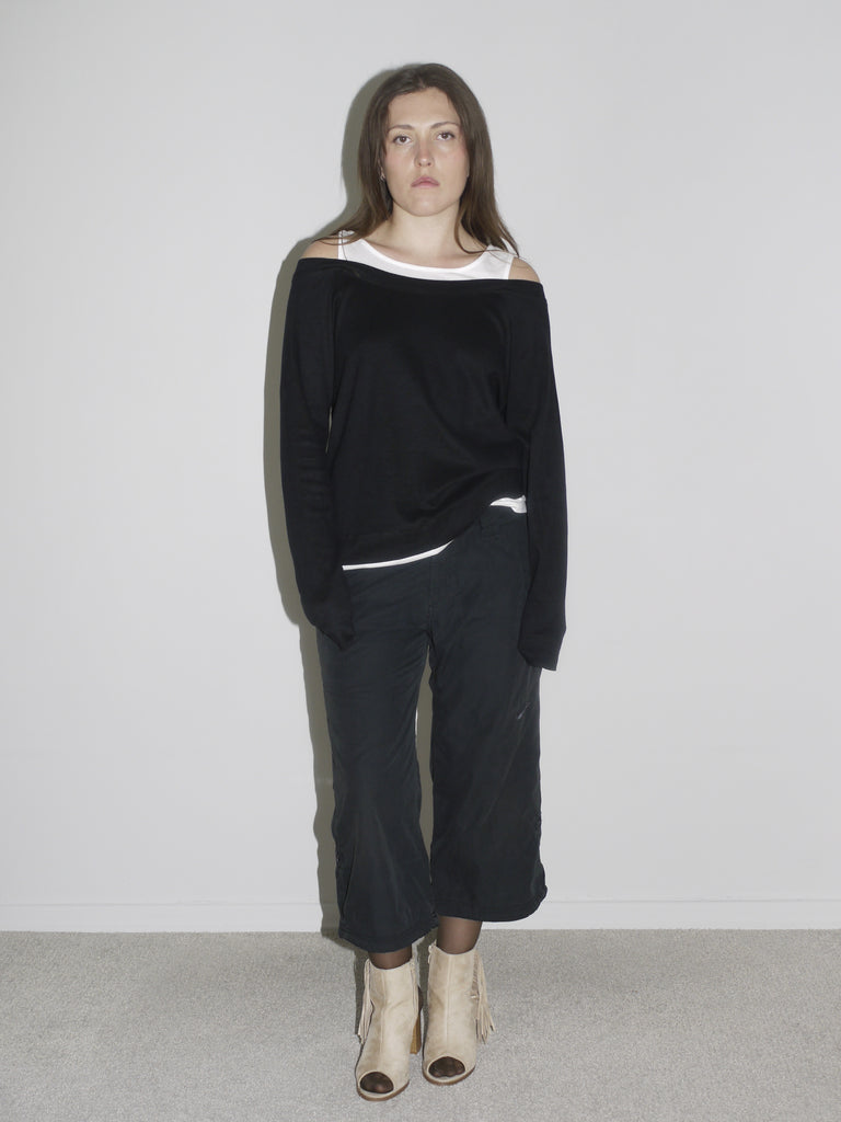 Model wearing layered off-shoulder black long-sleeve over a white tank top, paired with black G-Star inspired cargo pants and beige open-toe boots. A minimalistic, slouchy silhouette with a quiet edge — raw, undone, early 2000s cool.