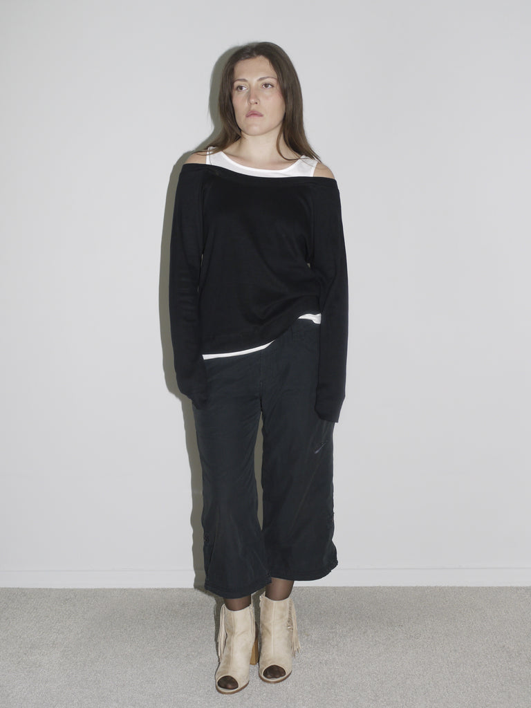 Model wearing layered off-shoulder black long-sleeve over a white tank top, paired with black G-Star inspired cargo pants and beige open-toe boots. A minimalistic, slouchy silhouette with a quiet edge — raw, undone, early 2000s cool.