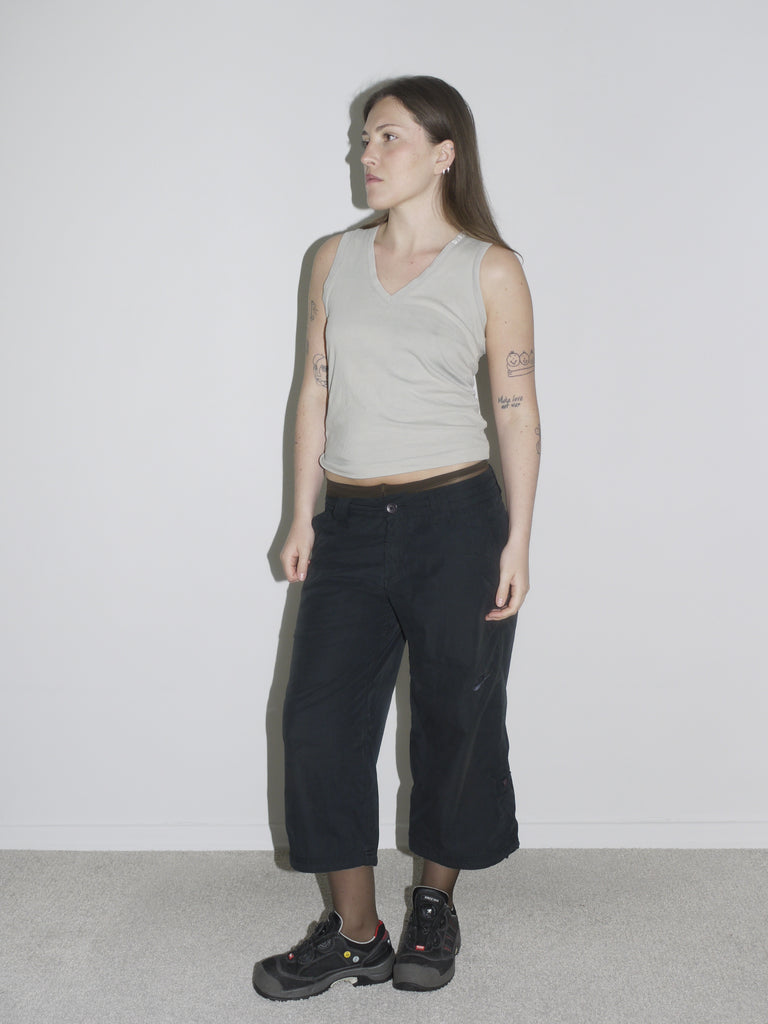 del wearing an original vintage Diesel tank top in light grey, styled with low-rise black cargo pants in the style of G-Star Raw, paired with rugged black Salomon-style sneakers. The look blends early 2000s streetwear energy with minimal utilitarian aesthetics — think Diesel meets Raf Simons and Helmut Lang.