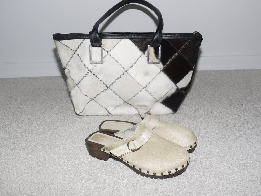 Close-up of a structured black and white cowhide patchwork handbag with black leather handles. Statement vintage piece with Margiela and Diesel vibes – bold, graphic, and collectible.