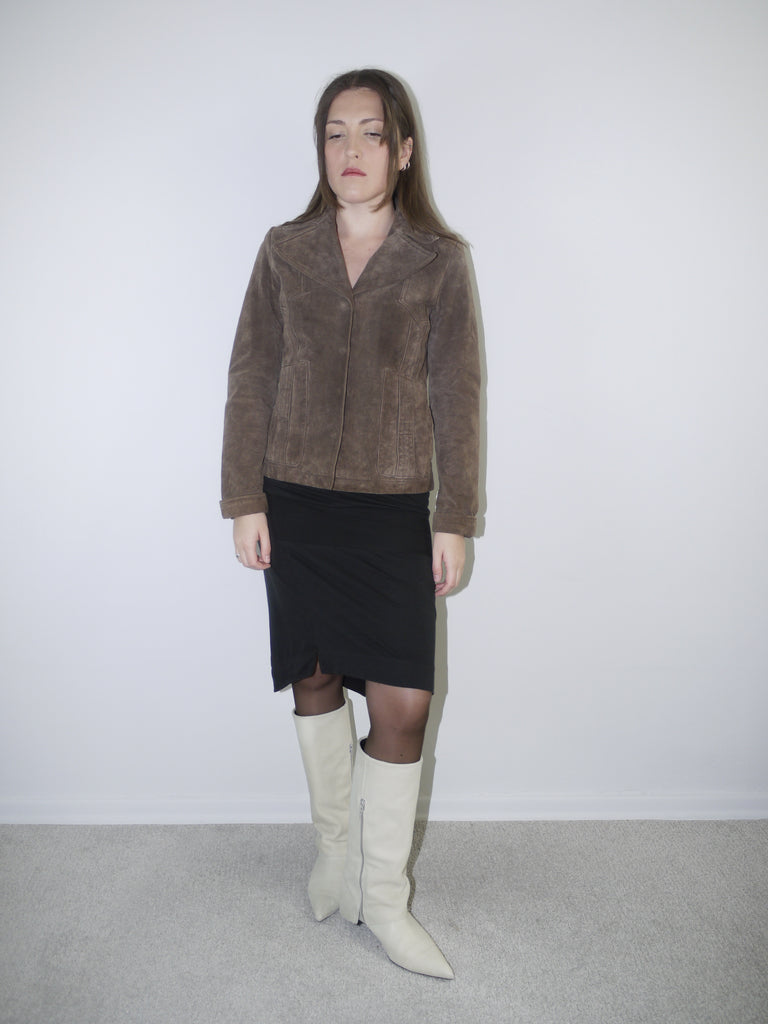 Model wearing a cropped brown faux fur jacket over a soft white vintage-style dress and black leather boots – Miu Miu inspired layered look with retro femininity.