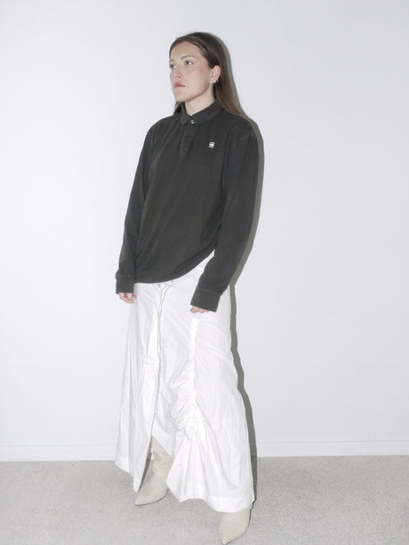 Vintage G-Star polo shirt in faded black with logo embroidery, styled with a white ruched full-length skirt and pointed knee-high boots—casual meets contemporary tailoring.