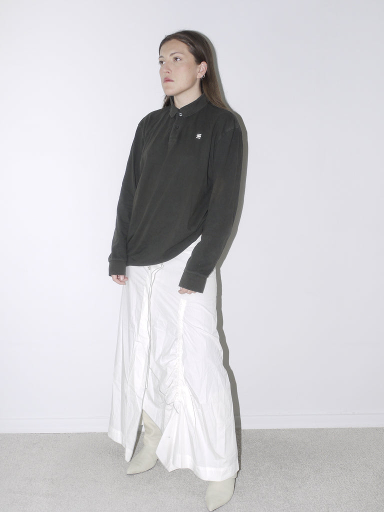 Vintage G-Star polo shirt in faded black with logo embroidery, styled with a white ruched full-length skirt and pointed knee-high boots—casual meets contemporary tailoring.