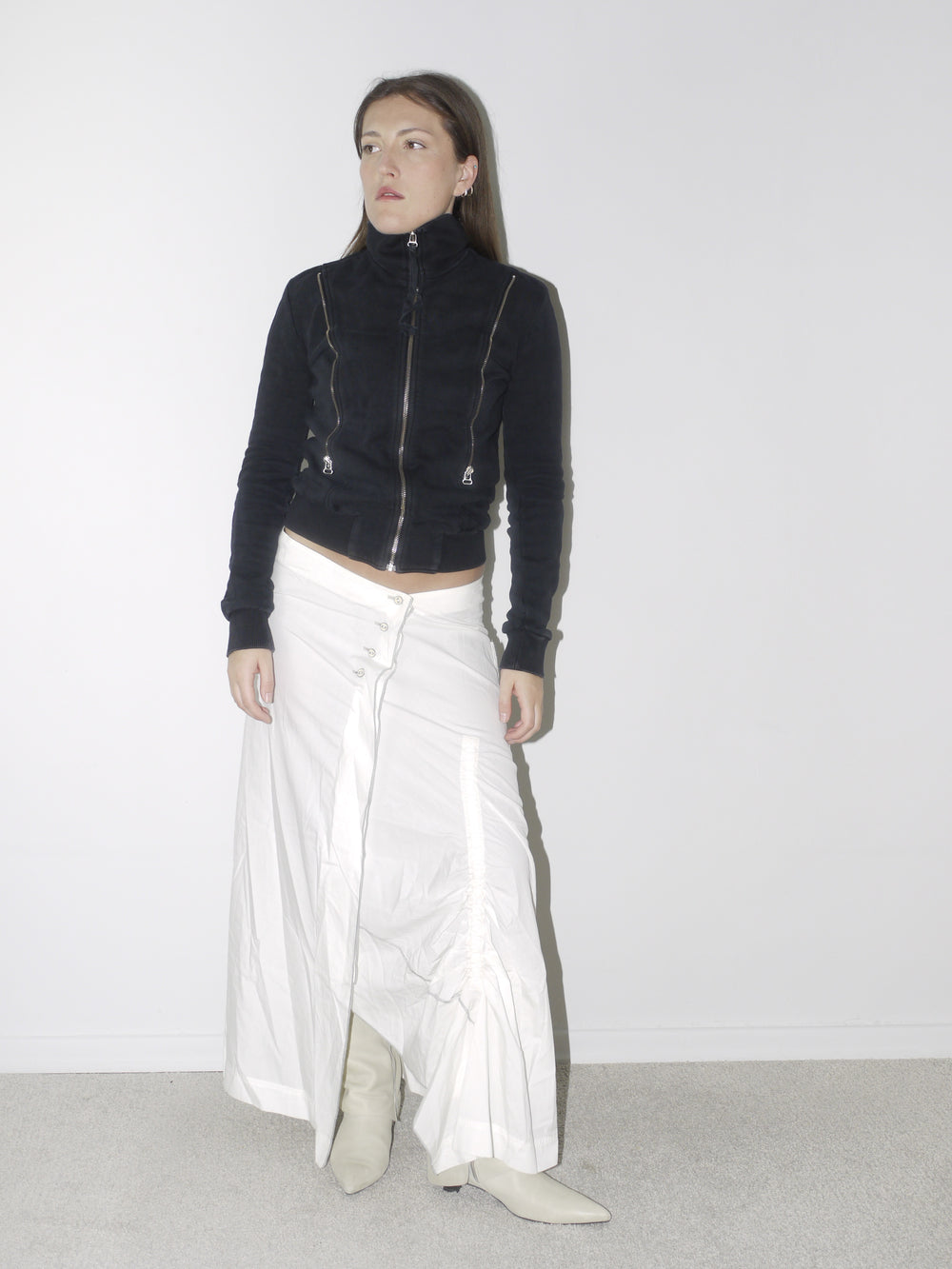 Original Maison Margiela black fitted zip-up jacket with high collar and visible seam detailing, styled with a ruched white maxi skirt and pointed cream boots – a refined, structured vintage piece with iconic tailoring.