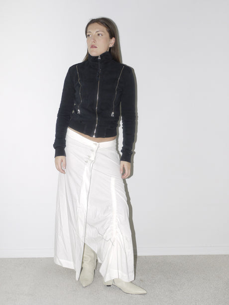 Original Maison Margiela black fitted zip-up jacket with high collar and visible seam detailing, styled with a ruched white maxi skirt and pointed cream boots – a refined, structured vintage piece with iconic tailoring.