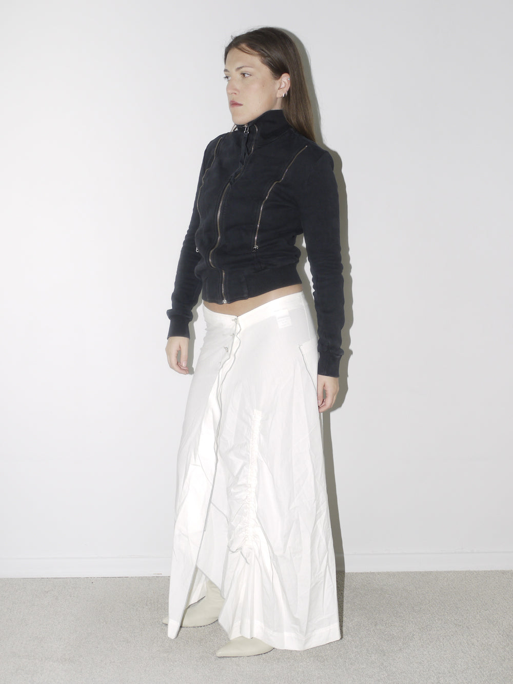 Original Maison Margiela black fitted zip-up jacket with high collar and visible seam detailing, styled with a ruched white maxi skirt and pointed cream boots – a refined, structured vintage piece with iconic tailoring.