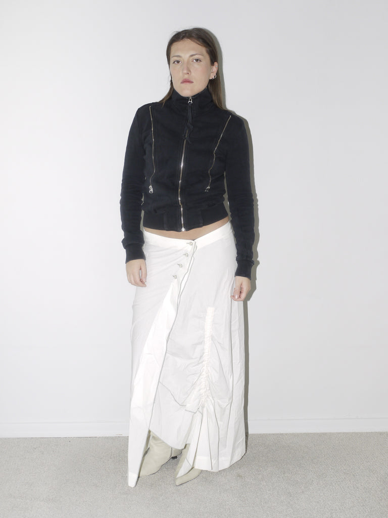 Original Maison Margiela black fitted zip-up jacket with high collar and visible seam detailing, styled with a ruched white maxi skirt and pointed cream boots – a refined, structured vintage piece with iconic tailoring.