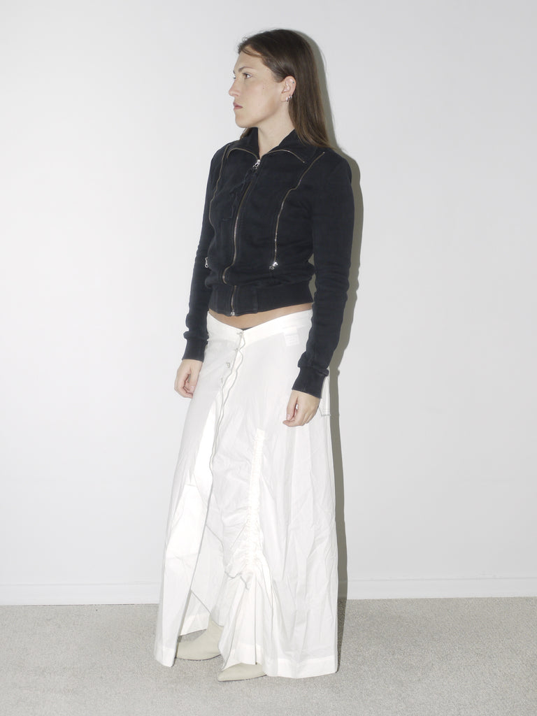 Original Maison Margiela black fitted zip-up jacket with high collar and visible seam detailing, styled with a ruched white maxi skirt and pointed cream boots – a refined, structured vintage piece with iconic tailoring.