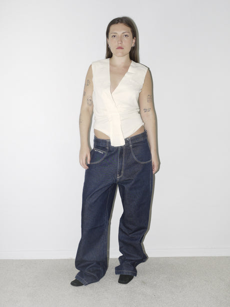 Original Maison Margiela cream sleeveless top with asymmetric button detail, styled with oversized dark denim jeans for a contemporary deconstructed look.