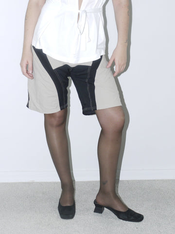 Vintage Diesel halter top in crisp white with deep plunge neckline and waist tie, styled with two-tone tech shorts and kitten heels for a bold Y2K-inspired look.