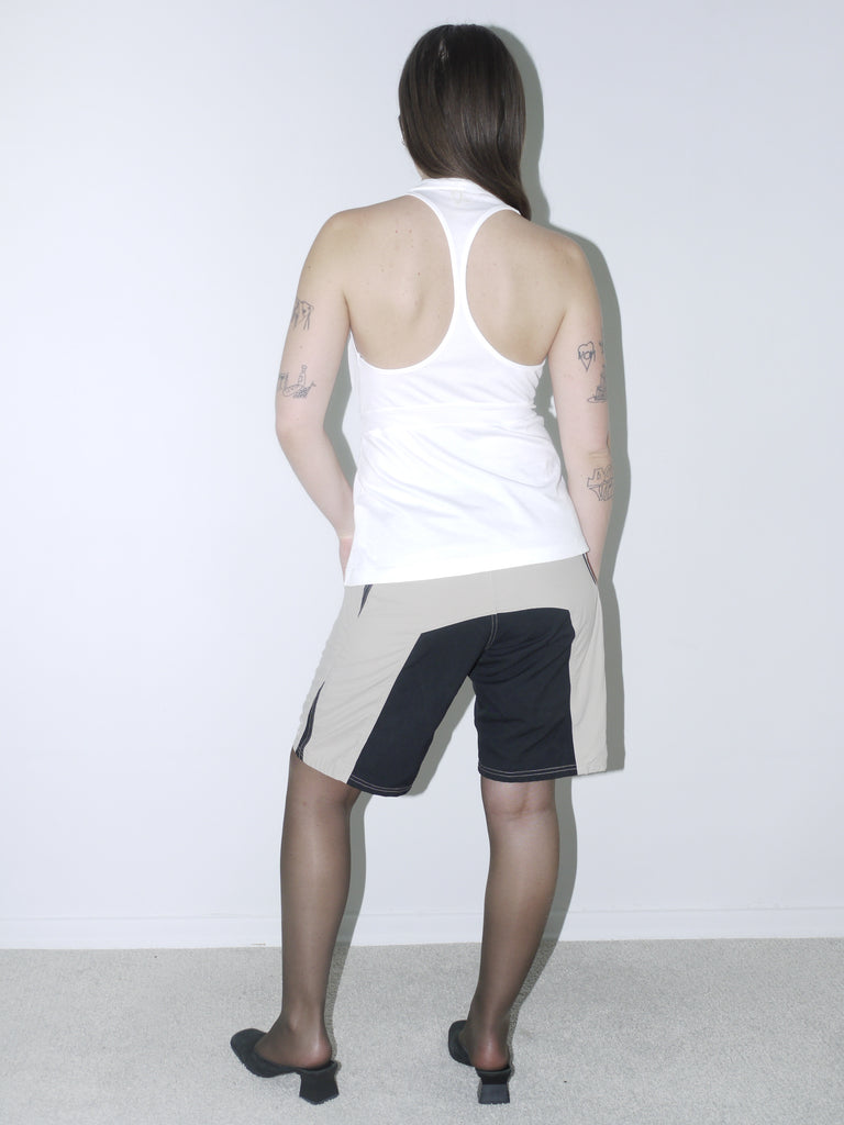 Vintage Diesel halter top in crisp white with deep plunge neckline and waist tie, styled with two-tone tech shorts and kitten heels for a bold Y2K-inspired look.