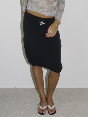 Model wearing a sheer long-sleeve lace top in light grey over a black bra, paired with a black midi skirt featuring a side brooch detail. Styled with flip-flops and silver jewelry for a feminine yet bold Y2K-inspired look. Shot against a plain white wall.