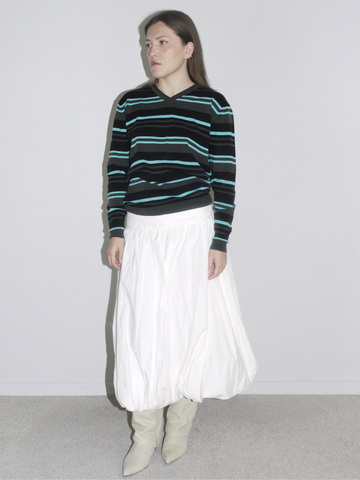 Model wearing a black long sleeve with mint and blue horizontal stripes, tucked into a voluminous white balloon skirt and styled with off-white cowboy boots. A laid-back vintage look blending skater Y2K with Cocaletto’s signature softness.