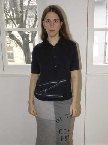 Vintage Miu Miu black short-sleeve knit top with a classic collar and button-down front, featuring a slightly cropped fit. Styled with a grey maxi skirt featuring statement text print for a playful yet refined look.